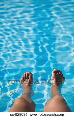 Stock Photography - Man with feet in swimming pool. Fotosearch