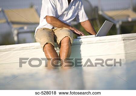 Man with laptop by swimming pool View Large Photo Image Stock Photo - Man with laptop by swimming pool. Fotosearch