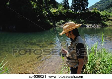 Stock Image - Man with straw hat and holding fishing rod. Fotosearch