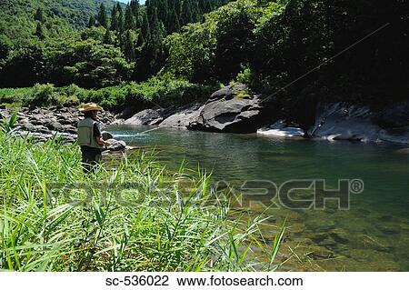 Stock Image - Man with straw hat and holding fishing rod. Fotosearch