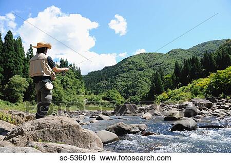 Man with straw hat standing and holding fishing rod View Large Photo Image Stock Photograph - Man with straw hat standing and holding fishing rod. Fotosearch