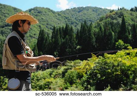 Stock Photography - Man with straw hat standing and holding fishing rod. Fotosearch