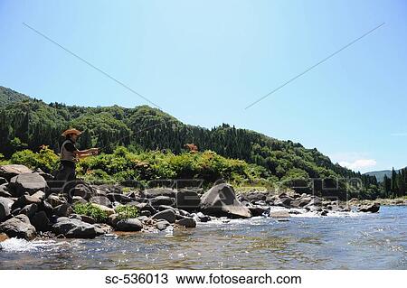 Man with straw hat standing on stone and fishing View Large Photo Image Stock Image - Man with straw hat standing on stone and fishing. Fotosearch