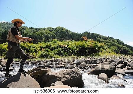 Man with straw hat standing on stone and holding fishing rod View Large Photo Image Stock Photograph - Man with straw hat standing on stone and holding fishing rod. Fotosearch