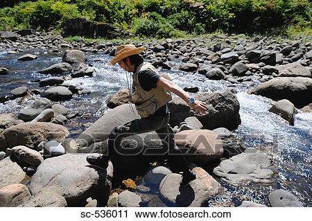 Man with straw hat walking on stones View Large Photo Image Stock Image - Man with straw hat walking on stones. Fotosearch