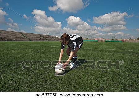 Stock Image - Player placing soccer ball in center circle. Fotosearch