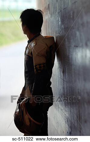 Stock Image - Rear profile of racing motor biker standing by wall. Fotosearch
