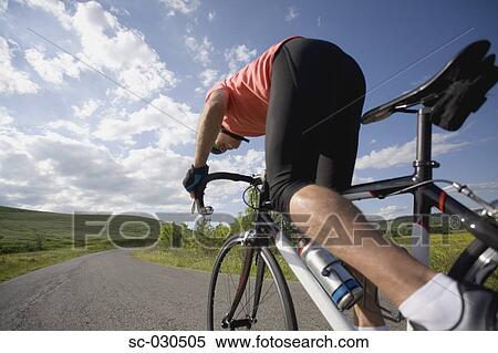 Rear view of a man cycling on road with cloudy sky View Large Photo Image Stock Photography - Rear view of a man cycling on road with cloudy sky. Fotosearch