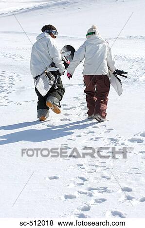 Rear view of snowboarders walking in snow View Large Photo Image Stock Photo - Rear view of snowboarders walking in snow. Fotosearch