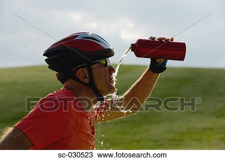 Stock Image - Side view of a cyclist drinking water. Fotosearch