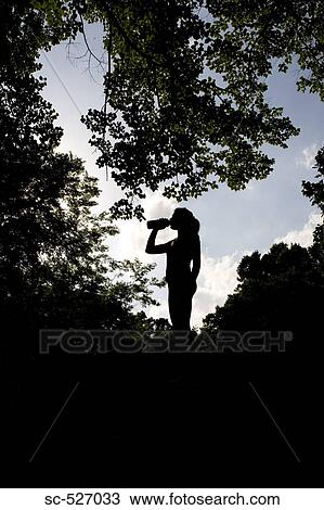 Stock Image - Silhouette of a Jogger relaxing and drinking water. Fotosearch