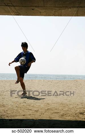 Stock Image - Silhouette Of a Young Man With a Soccer Ball on the Beach. Fotosearch