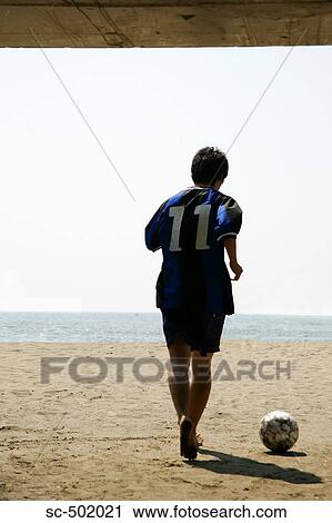 Stock Image - Silhouette Of a Young Man With a Soccer Ball on the Beach. Fotosearch