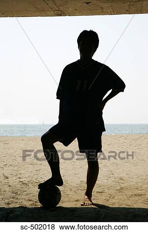 Stock Photo - Silhouette Of a Young Man With a Soccer Ball on the Beach. Fotosearch