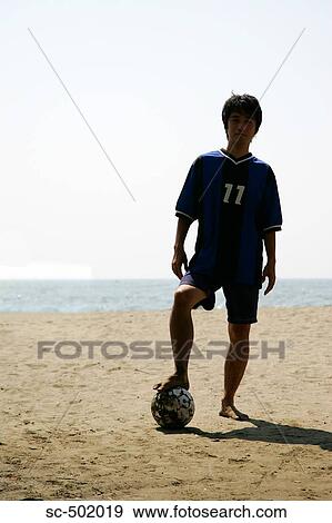 Stock Photo - Silhouette Of a Young Man With a Soccer Ball on the Beach. Fotosearch