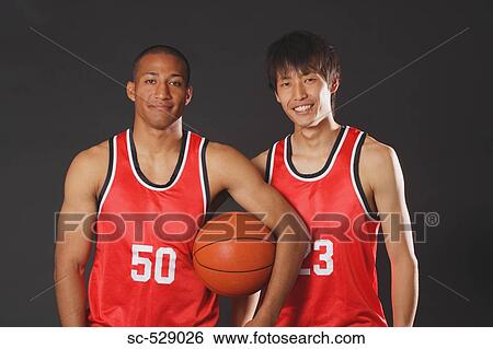 Stock Photograph - Smiling young men posing with basketball. Fotosearch