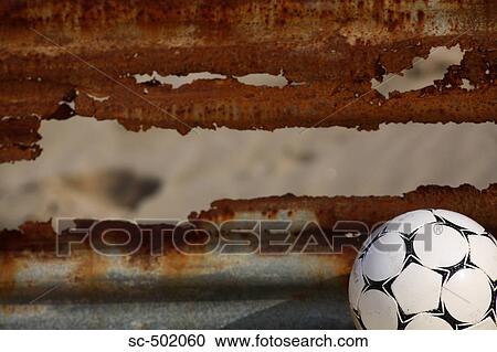 Stock Image - Soccer ball and corrugated tin wall. Fotosearch