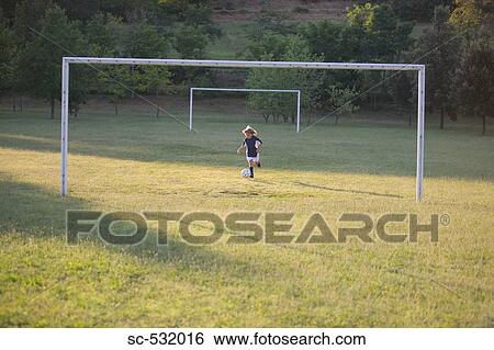 Stock Photograph - Soccer boy kicking soccer ball at goal post. Fotosearch