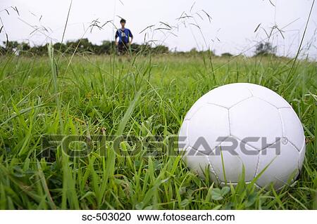 Stock Image - Soccer Player And A Soccer Ball In a Field. Fotosearch