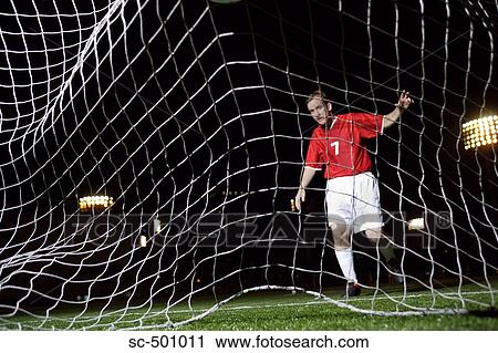 Stock Image - Soccer Player Behind Waving Net. Fotosearch