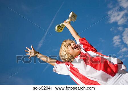 Stock Image - Soccer player cheering with trophy. Fotosearch