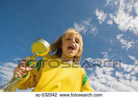 Stock Image - Soccer player cheering with trophy. Fotosearch