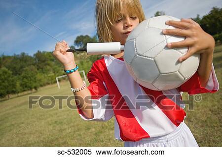 Stock Photography - Soccer player holding football and pumping air . Fotosearch