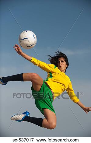 Stock Photo - Soccer player in midair kicking soccer ball. Fotosearch