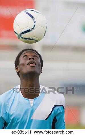 Stock Image - Soccer player juggling ball on head. Fotosearch