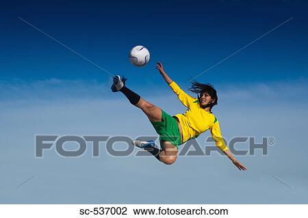 Stock Image - Soccer player kicking soccer ball . Fotosearch