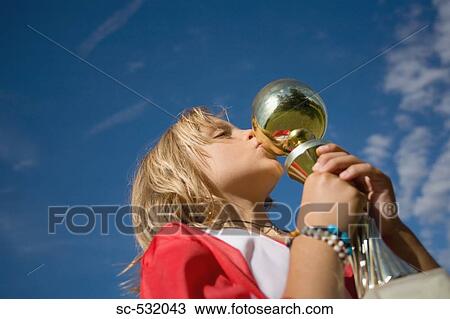 Stock Image - Soccer player kissing trophy cup. Fotosearch