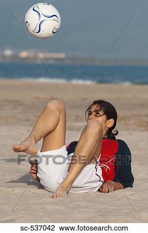 Stock Image - Soccer player playing beach soccer. Fotosearch