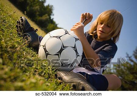 Picture - Soccer player pumping air into football. Fotosearch