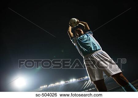 Stock Photograph - Soccer Player Raising Ball In Victory. Fotosearch