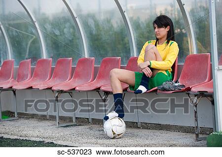 Stock Image - Soccer player relaxing in dugout. Fotosearch