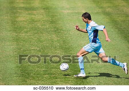 Stock Image - Soccer player running with ball. Fotosearch