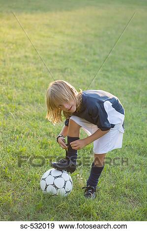 Stock Photo - Soccer player tying laces on on football. Fotosearch