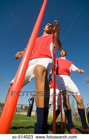 Stock Image - Soccer players dodging through poles. Fotosearch