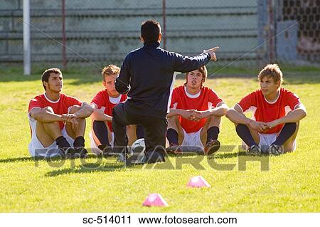 Stock Image - Soccer players listening to the coach. Fotosearch