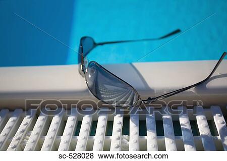 Stock Photo - Sunglasses at the edge of swimming pool. Fotosearch