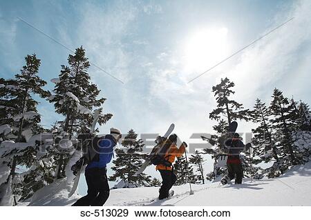 Stock Photo - Three snowboarders walking through snow. Fotosearch