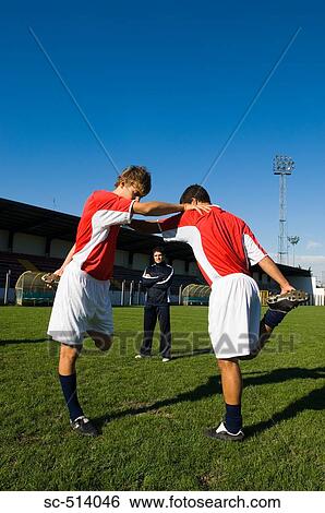 Two boys stretching as the coach looks on View Large Photo Image Stock Photograph - Two boys stretching as the coach looks on. Fotosearch