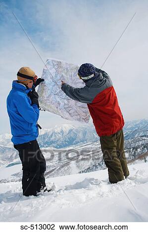 Stock Image - Two snowboarders checking map. Fotosearch