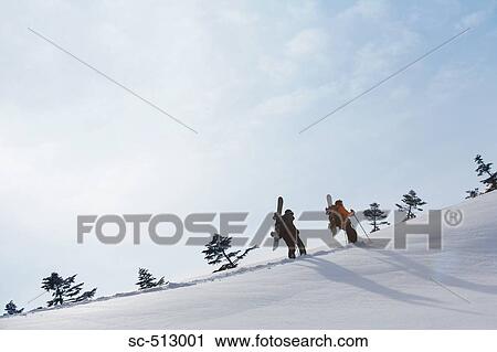 Two snowboarders walking through snow View Large Photo Image Stock Image - Two snowboarders walking through snow. Fotosearch