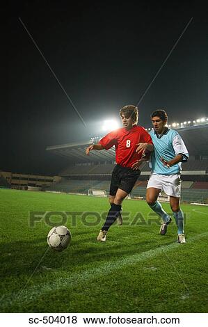 Two Soccer Players Chasing A Ball View Large Photo Image Stock Photo - Two Soccer Players Chasing A Ball. Fotosearch