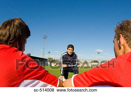 Stock Photo - Two soccer players listening to the coach. Fotosearch