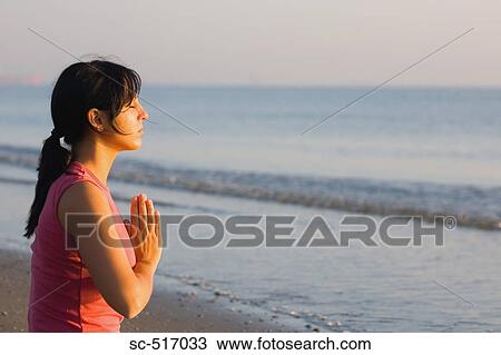 Stock Image - Woman Meditating On the Beach. Fotosearch