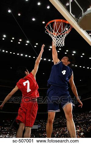 Stock Image - Young Asian basketball player making a dunk. Fotosearch