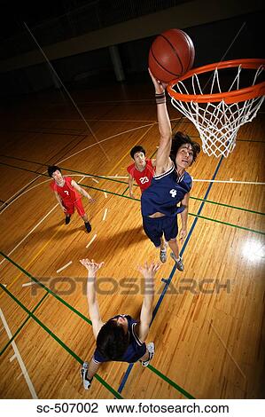 Stock Image - Young Asian basketball player making a dunk. Fotosearch