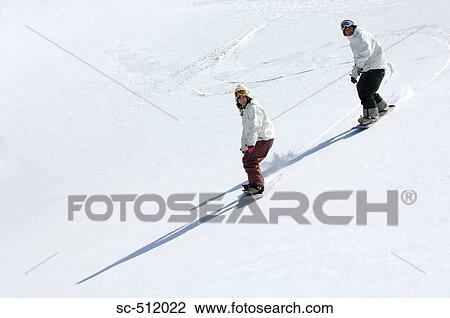 Stock Image - Young Asian snowboarders on slope. Fotosearch